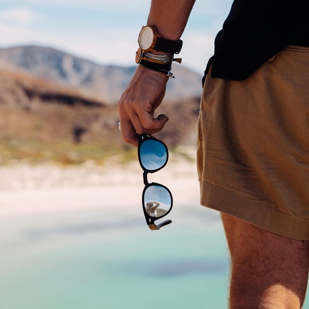 man wearing wooden accessories, hand holding Gowood wooden sunglasses