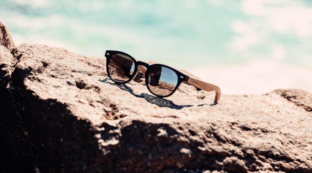 round wooden sunglasses on a rock at the beach