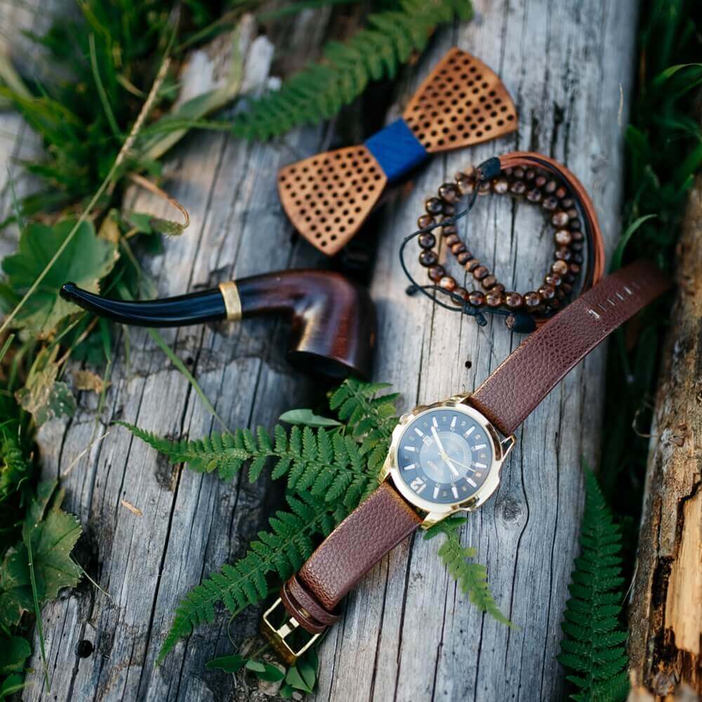 vegan watch, wooden bow tie, bracelet, and pipe on a log