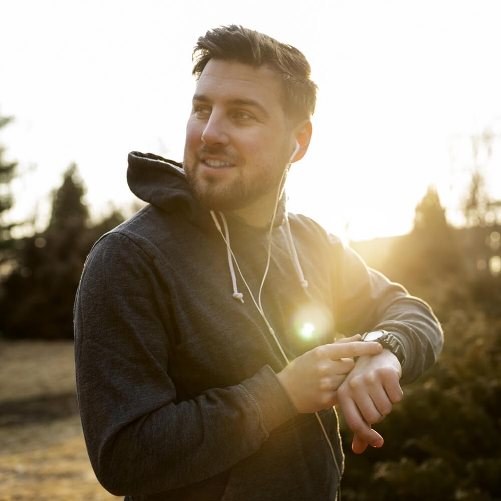 young man checking his solar-powered watch while exercising outdoors