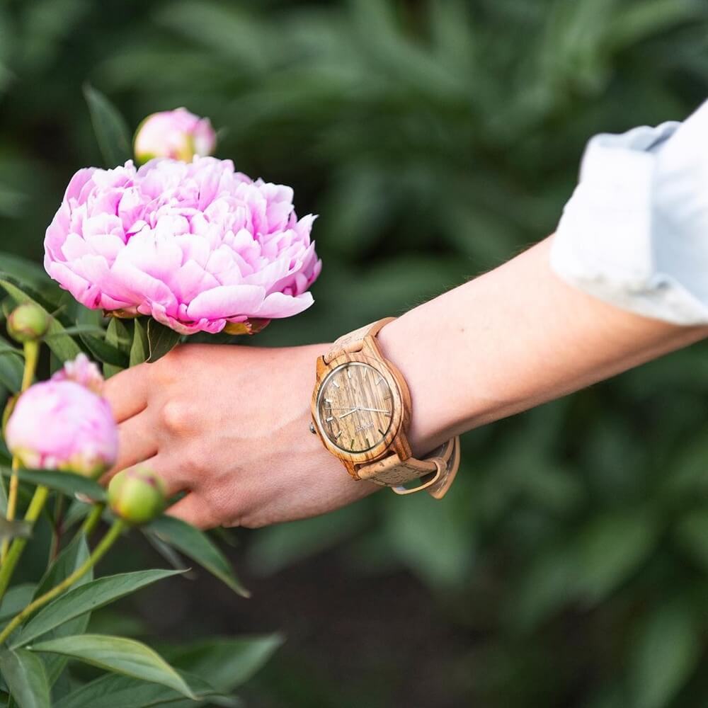 A close-up photo of a lady wearing a Gowood wooden watch and holding a pink flower for valentine's day 2024