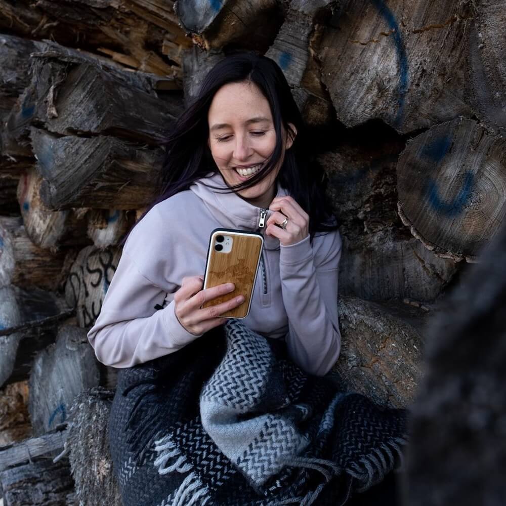 smiley woman holding her phone with a map design on the back