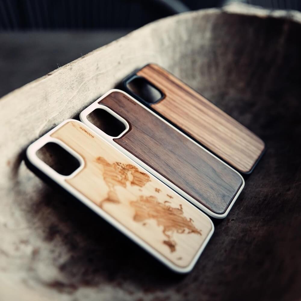 Three Gowood wooden phone cases with a world map design resting in a wooden bowl