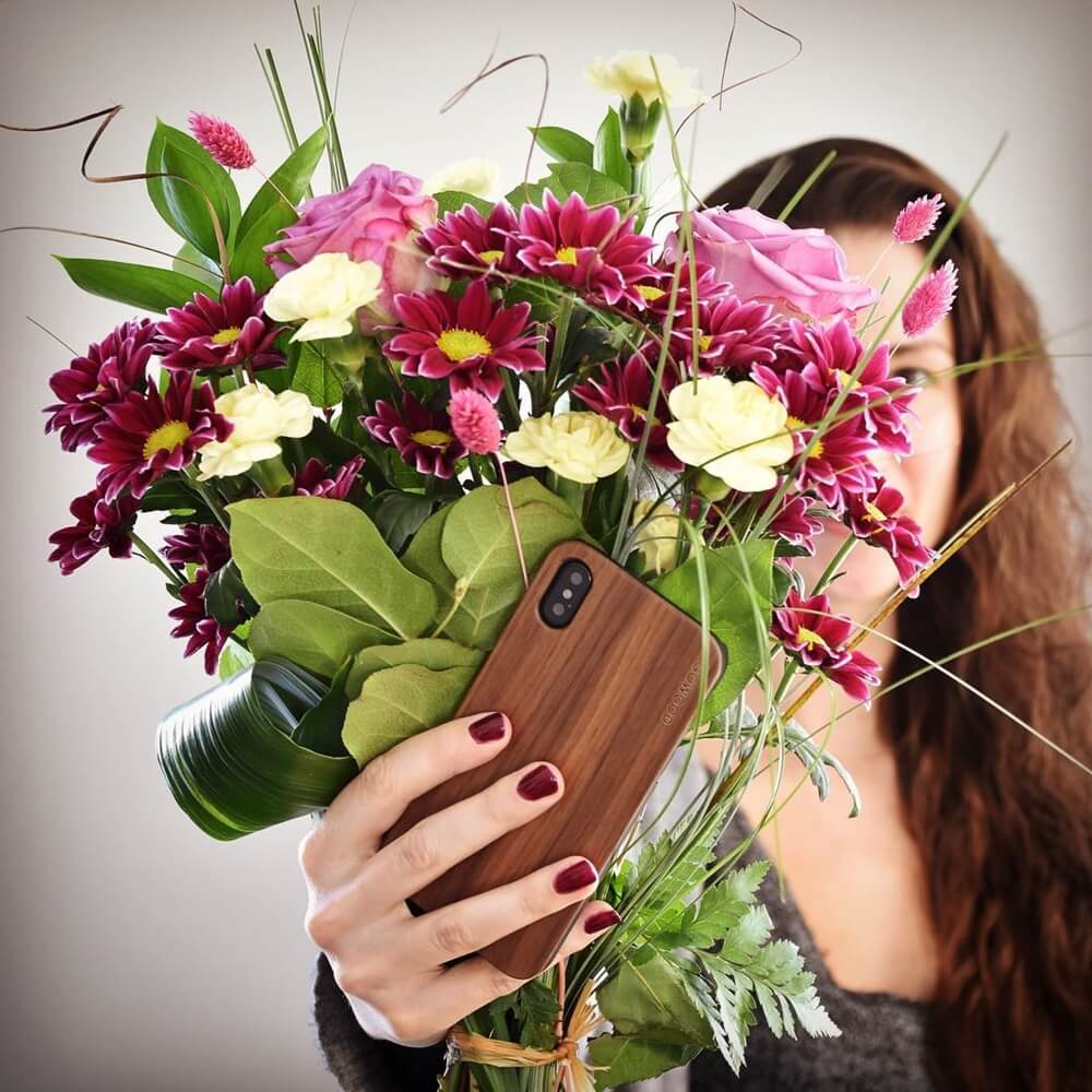 Young woman holding a beautiful flower bouquet and a her phone