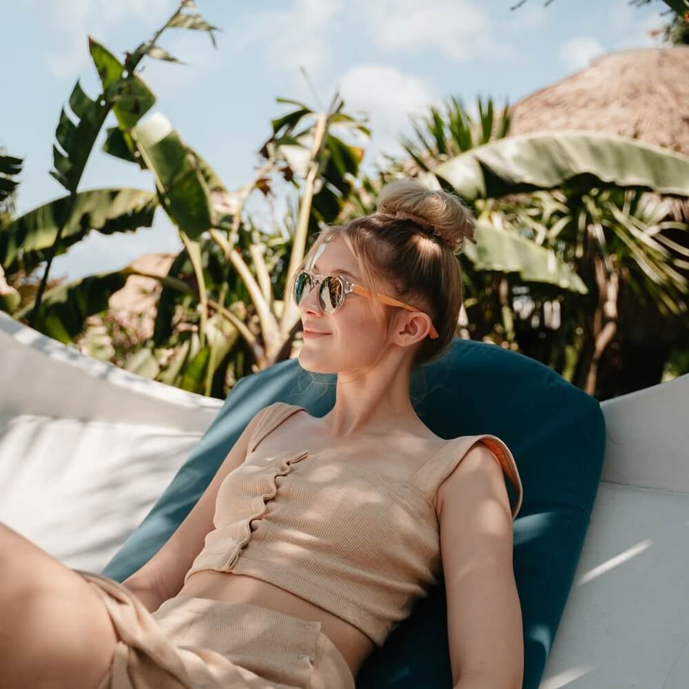 Young lady relawing while wearing Gowood Wood Sunglasses with Mirrored Lenses