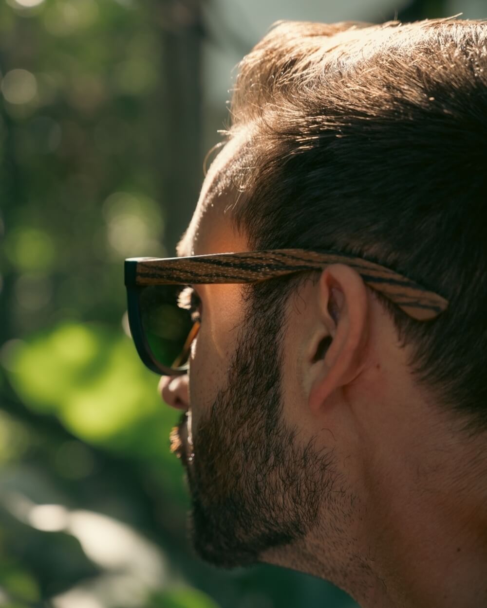 Close-up profile of a man wearing wooden sunglasses, capturing the essence of sunglasses in autumn