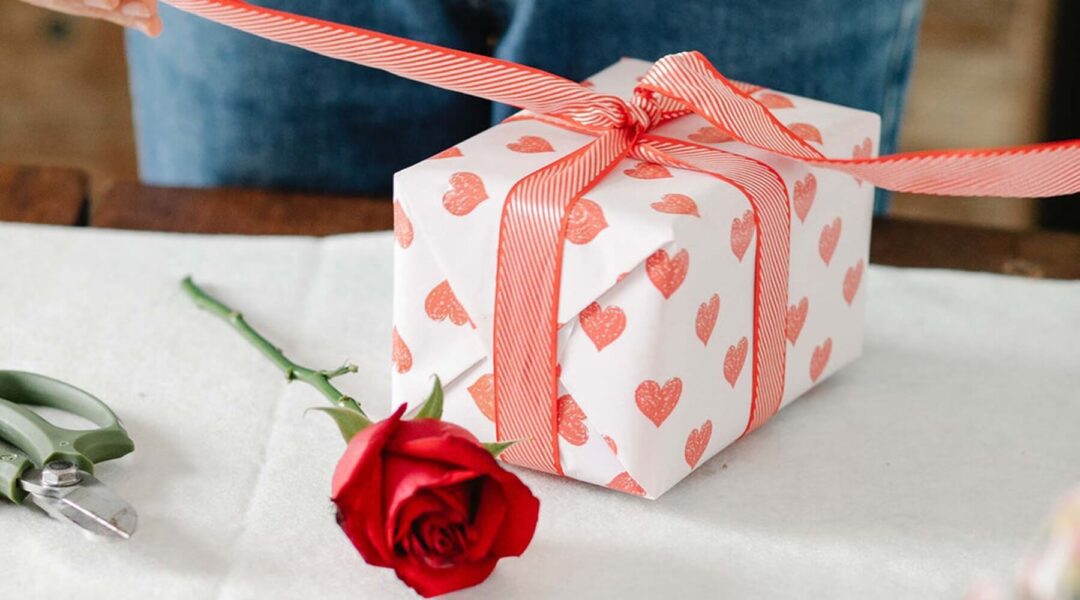 A gift box wrapped in heart-patterned paper suggests a romantic occasion that could also include valentine's sunglasses